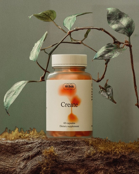 A high-end product photography shot featuring a dietary supplement bottle placed on a mossy log with a hanging plant, emphasizing natural ingredients.